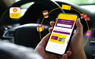 Pessoa está dentro de um carro com o celular nas mãos olhando a tela inicial do aplicativo Shell Box
